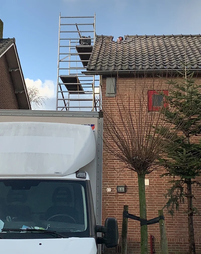 Een steiger langs de zijgevel van een woning; onderaan staat een bestelbus.